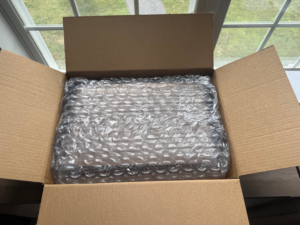 Open cardboard box with bubble-wrapped contents.

11x17 framed drawing reprints shipping box, inside contents.